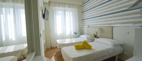 A hotel room with two beds, a large window with curtains, a flat-screen TV mounted on the wall, and a striped ceiling.