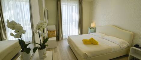A hotel room with a large bed, a bedside table, a nightstand, and a mirror.