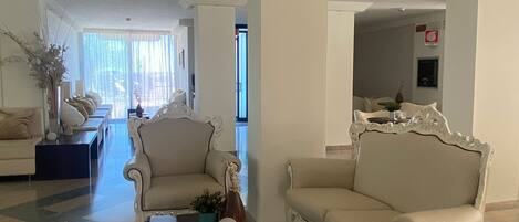 A spacious lobby with a checkered floor, two ornate armchairs, a dark coffee table, and a sofa.