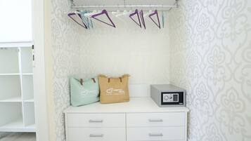 Una habitación ordenada con un tocador blanco, una radio pequeña y almohadones decorativos.