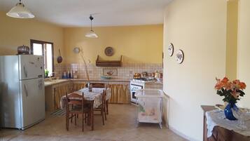 Cozinha compacta com geladeira, fogão e mesa de jantar.