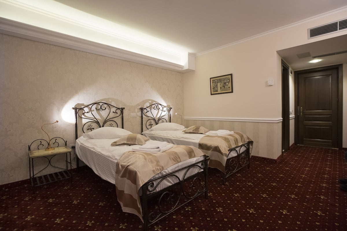 Une chambre d’hôtel avec deux lits, une petite table de chevet, un tableau accroché au mur et une porte.