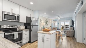 A modern kitchen with white cabinets, stainless steel appliances, and a wooden floor. - Time to get… 🎶 Knee deep in the water somewhere! 🎶 on island time! (Gulf Shores)