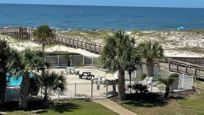 A beachside resort with a pool, palm trees, and a wooden boardwalk. - Time to get… 🎶 Knee deep in the water somewhere! 🎶 on island time! (Gulf Shores)