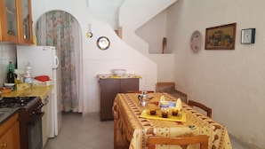Una cocina con estufa, refrigerador y una mesa de comedor dispuesta con tazas y una bandeja.