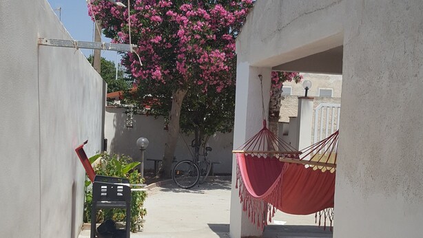 Un estrecho callejón con una hamaca, una bicicleta y un carrito.