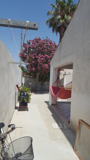 A narrow alleyway with a hammock, a bicycle, and a cart. - Casa Vacanza Cala Spaghetti (Mazara del Vallo)