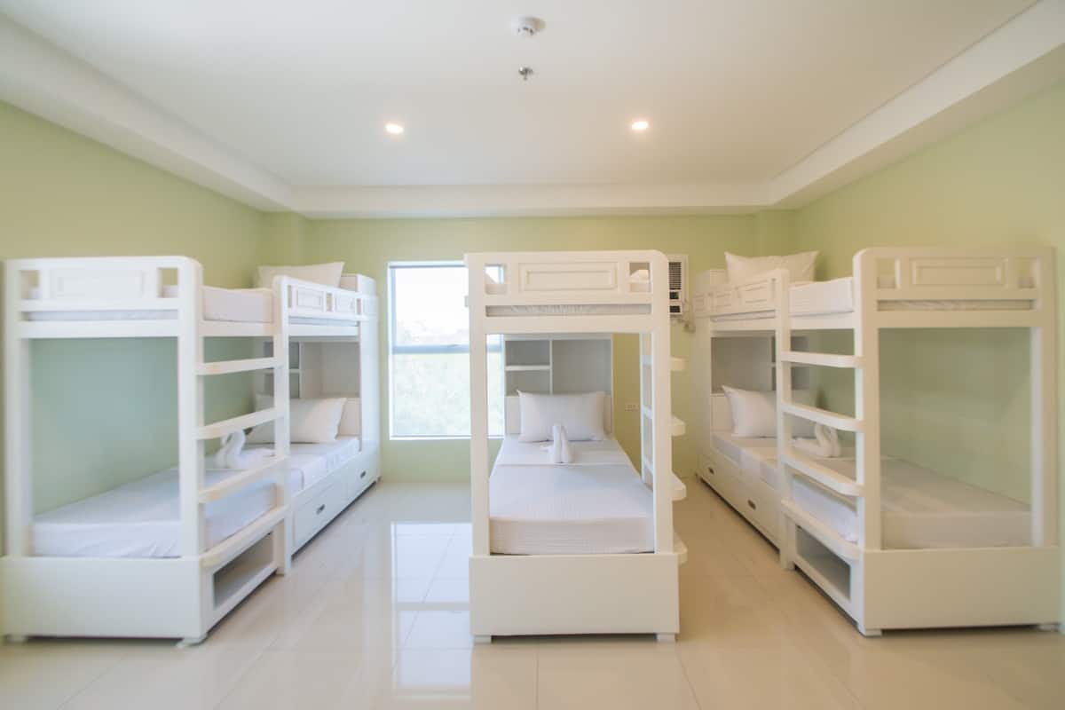 A room with bunk beds, a window, and a door.