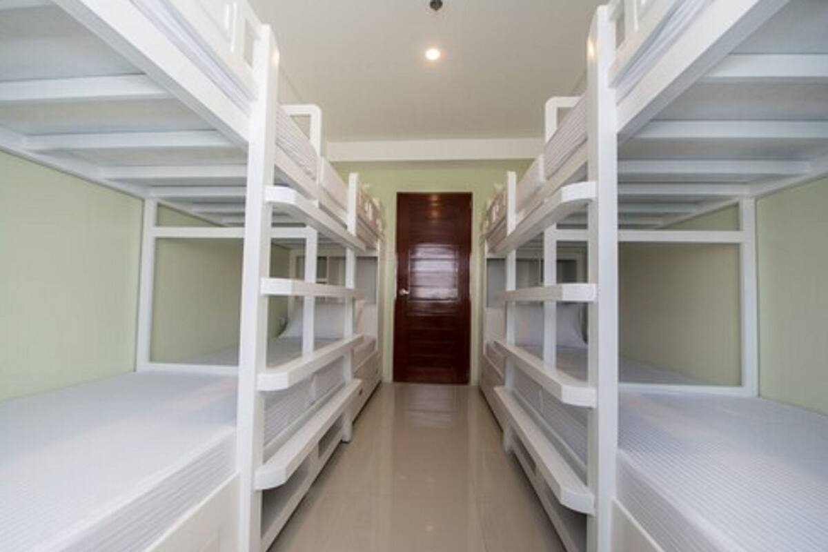 A corridor with bunk beds on either side, leading to a door at the end.