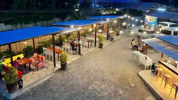 An outdoor dining area with tables and chairs, surrounded by potted plants and a covered seating area. - Shore Time Dormitel - Hostel (Boracay Island)