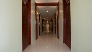 A long, narrow hallway with wooden doors on either side and a shiny tiled floor. - Shore Time Dormitel - Hostel (Boracay Island)