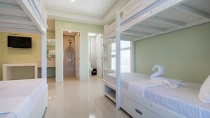 A hotel room with bunk beds, a television, a bathroom, and a hallway leading to another room. - Shore Time Dormitel - Hostel (Boracay Island)