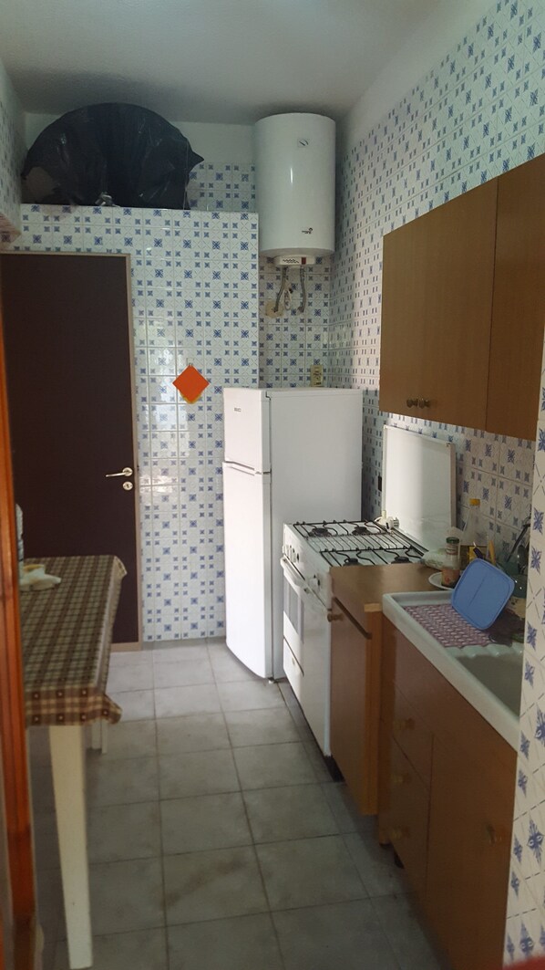 A compact kitchen with a refrigerator, stove, and a water heater.