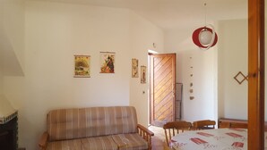 Una sala de estar con un sofá a rayas, una mesa de comedor con mantel estampado y obras de arte colgadas en la pared.