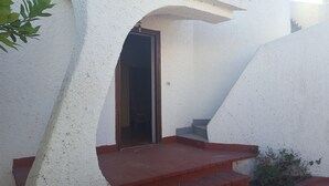 Una escalera estrecha que conduce a un interior oscuro, rodeada de paredes blancas con textura.