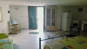 A room with a bed, a desk, a chair, a television, a refrigerator, and a cabinet.