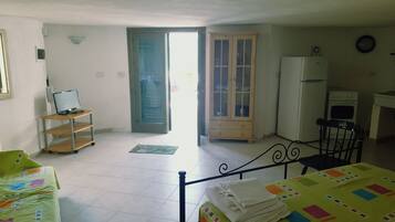 Quarto com cama, escrivaninha, cadeira, televisão, frigorífico e armário.