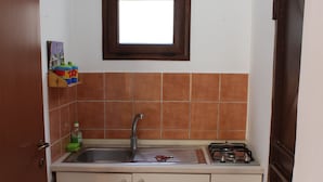 A compact kitchen with a sink, stove, and a window above the countertop. - Viriglio Apartment (Mazara del Vallo)