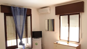 A room with a bed, a dresser, a television on a mini-fridge, and a window with blinds. - Viriglio Apartment (Mazara del Vallo)