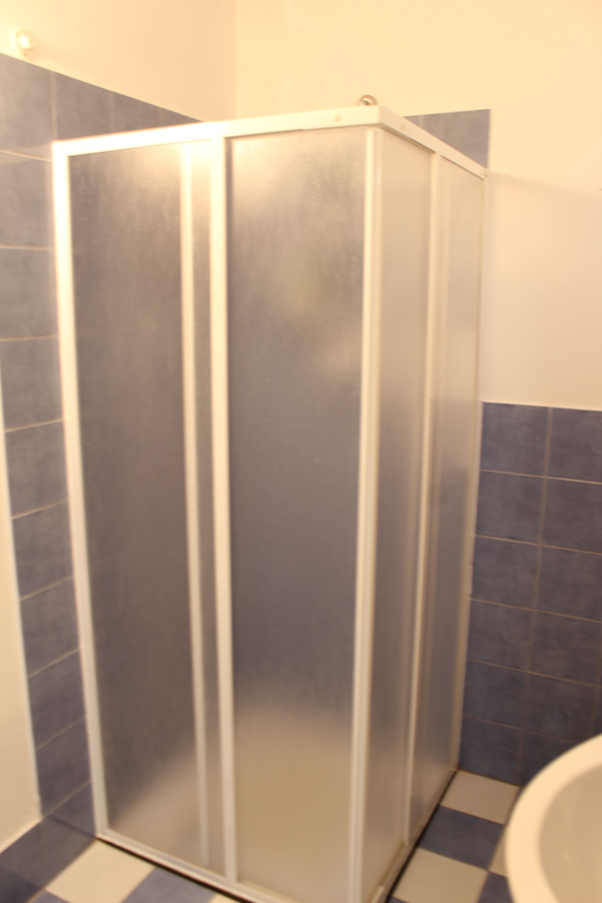 Un bagno con doccia, servizi igienici e pavimento in piastrelle a scacchi.