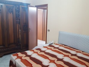 A bedroom with a bed, a wardrobe, and a door leading to another room.