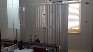 A modern bathroom with a large mirror, a sink, a toilet, and a shower area. - Villa Valeria (Mazara del Vallo)