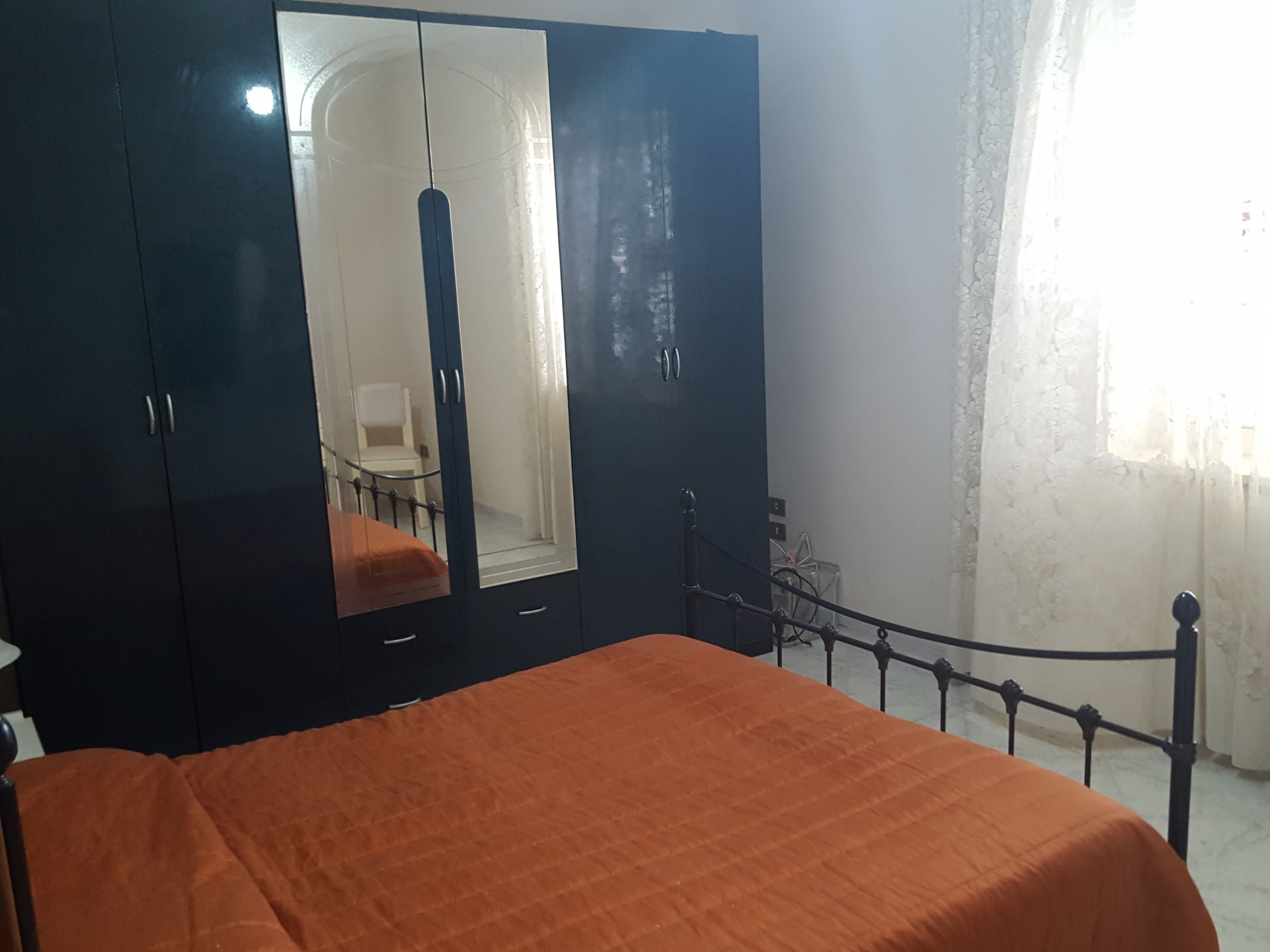 Quarto com cama, guarda-roupa e espelho.