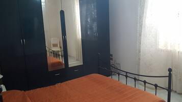 Quarto com cama, guarda-roupa e espelho.