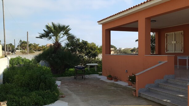 A residential building with a covered patio area, a palm tree, and potted plants. - Villa Valeria (Mazara del Vallo)