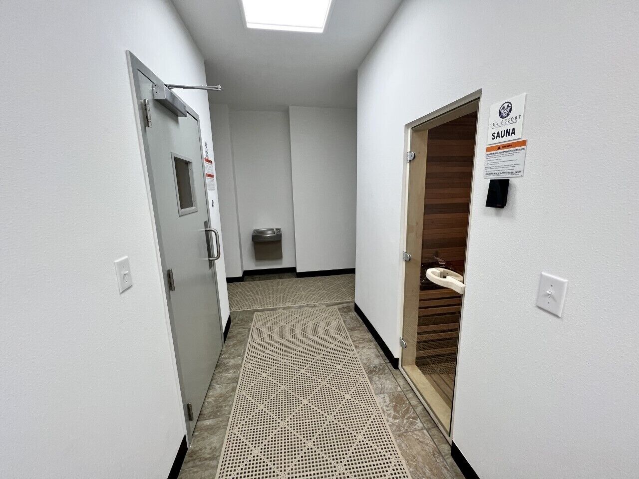 Ein Hotelkorridor mit Sauna-Hinweis, einer Futternapf und einer Tür für Haustiere.