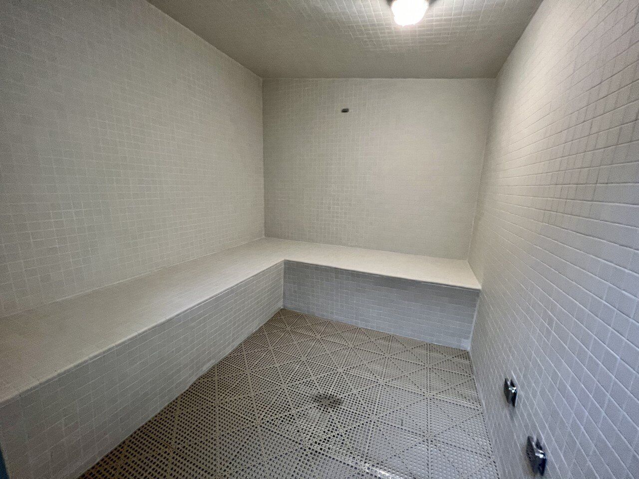Un baño pequeño con azulejos, un banco y una zona de ducha.
