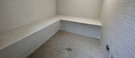 Un baño pequeño con azulejos, un banco y una zona de ducha.