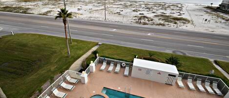 Un espace piscine doté de chaises longues, d’un jacuzzi et offrant une vue sur la plage et l’océan.