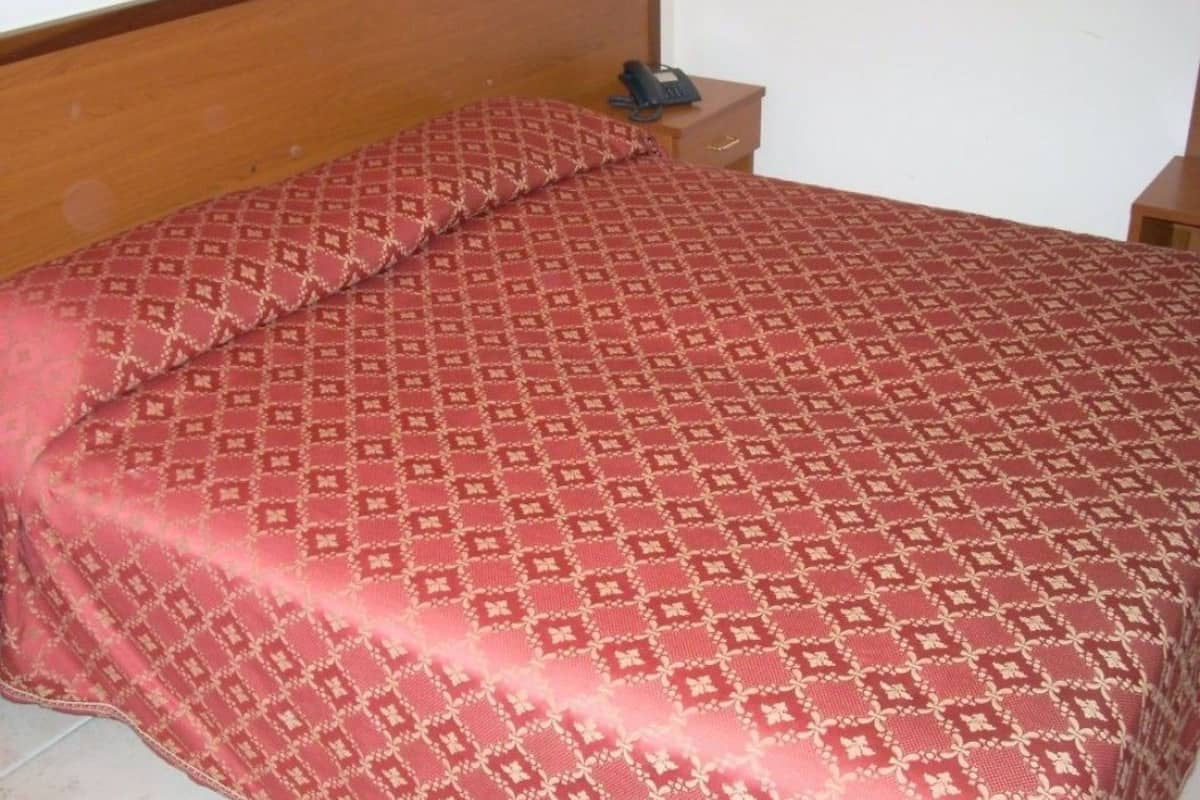 Ein ordentlich bezogenes Bett mit einem gemusterten Bettbezug und passenden Kissen.