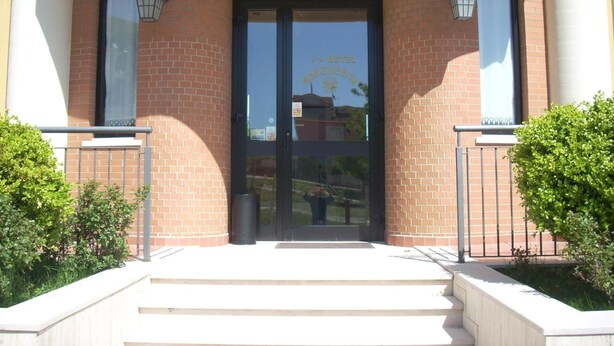 L’entrée d’un hôtel, avec une façade en briques, une double porte et deux lanternes fixées aux murs.