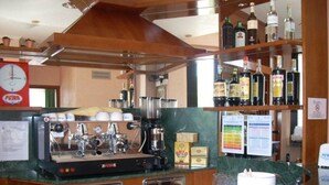 Un espace bar équipé d’une machine à café, d’étagères remplies de bouteilles d’alcool et d’une horloge.