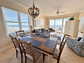 Enjoy ocean views from the comfort of this spacious living room, featuring a large dining table and comfortable seating.