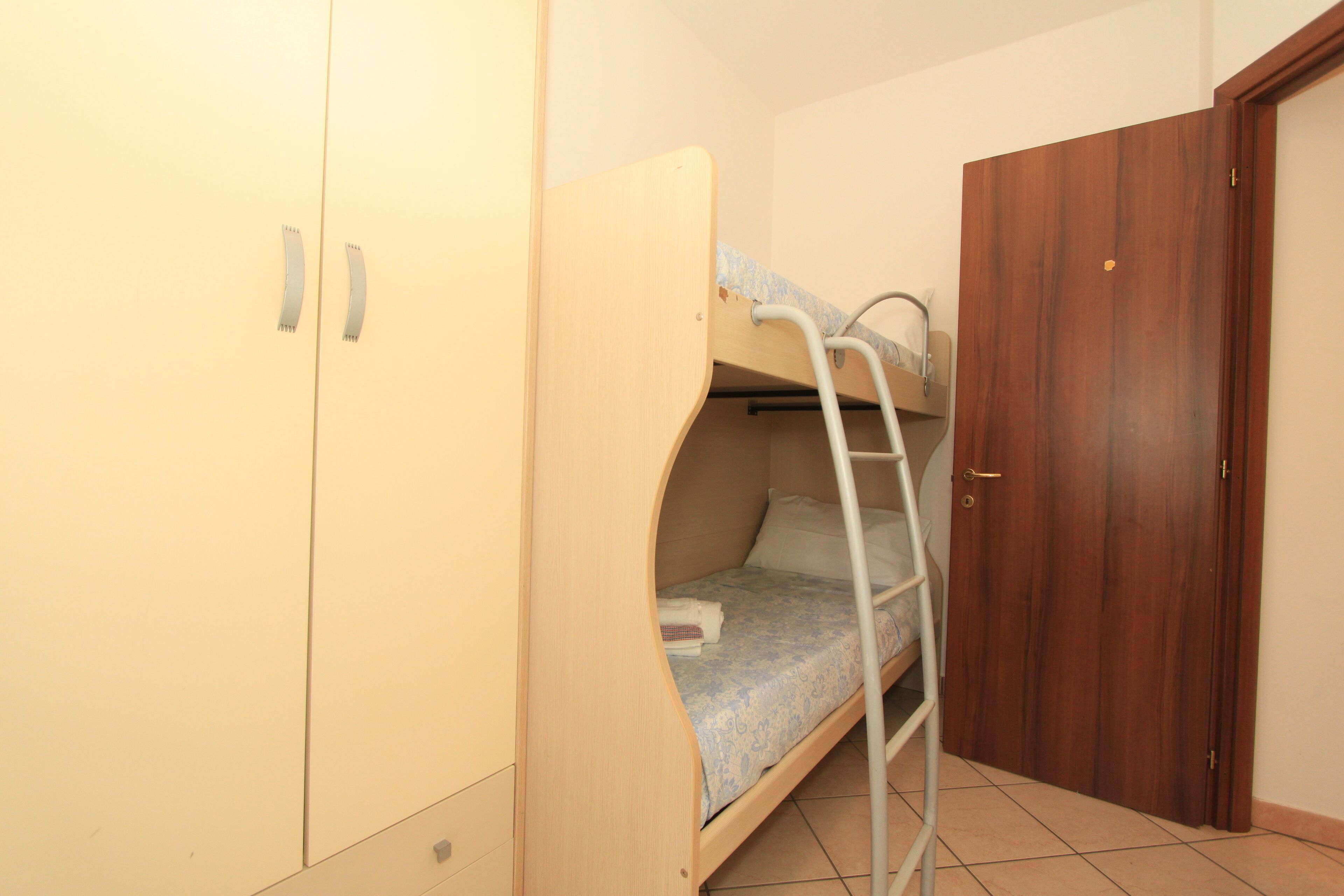 Un dormitori amb un llit superposat, un armari i una porta.