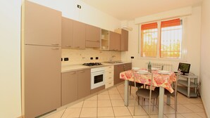 Una cocina compacta con comedor, que incluye estufa, horno y una mesa de comedor para dos.