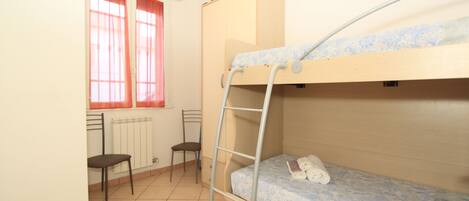 A bunk bed room with a ladder, a desk, and two chairs.