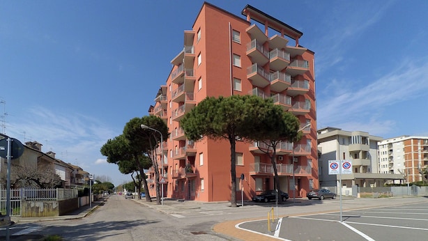 Un edificio residencial de varios pisos con balcones y un paso de peatones.