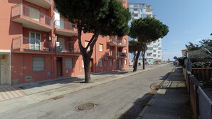 Una calle residencial con edificios de varios pisos, árboles y cielo despejado.