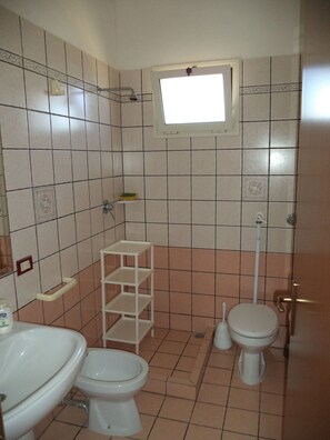 Une salle de bain équipée de toilettes, d’un lavabo et d’une fenêtre située au-dessus des toilettes.