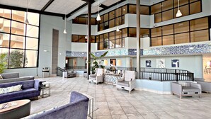 A spacious lobby with high ceilings, large windows, and multiple seating areas including sofas and armchairs. - Relax and Catch a couple of fish! 🎣 ~ There is something for everyone! (Orange Beach)