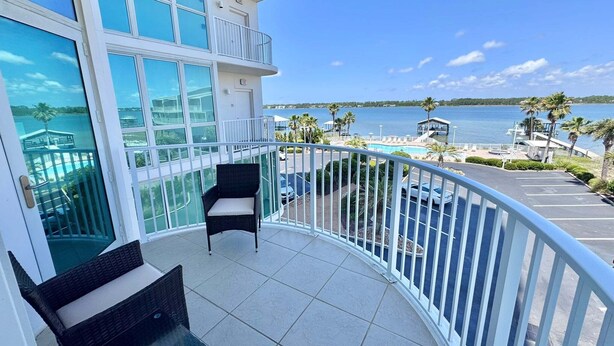 Ein Balkon mit Blick auf Strand und Pool, möbliert mit Korbstühlen und einem Tisch.