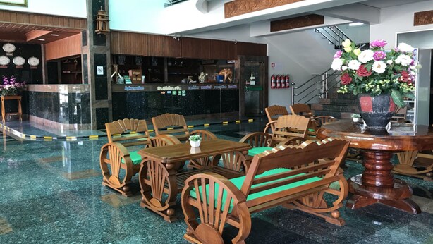 Un vestíbulo con mobiliario de madera, mostrador de recepción y una escalera.
