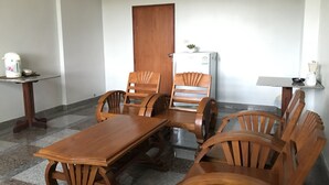 Un comedor con una mesa y sillas de madera, un refrigerador y una mesita con una planta.