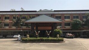 Un edificio con acceso cubierto, zona de estacionamiento y un camión estacionado afuera.