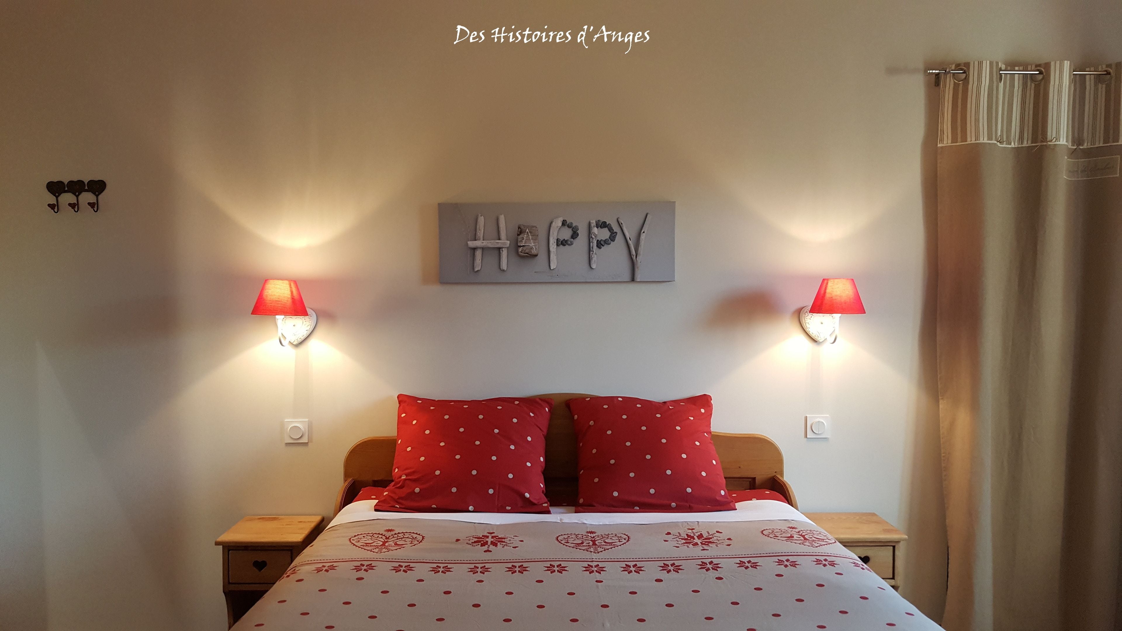 Quarto com cama, duas mesas de cabeceira, luminária na parede e um letreiro com a palavra 'Happy'.