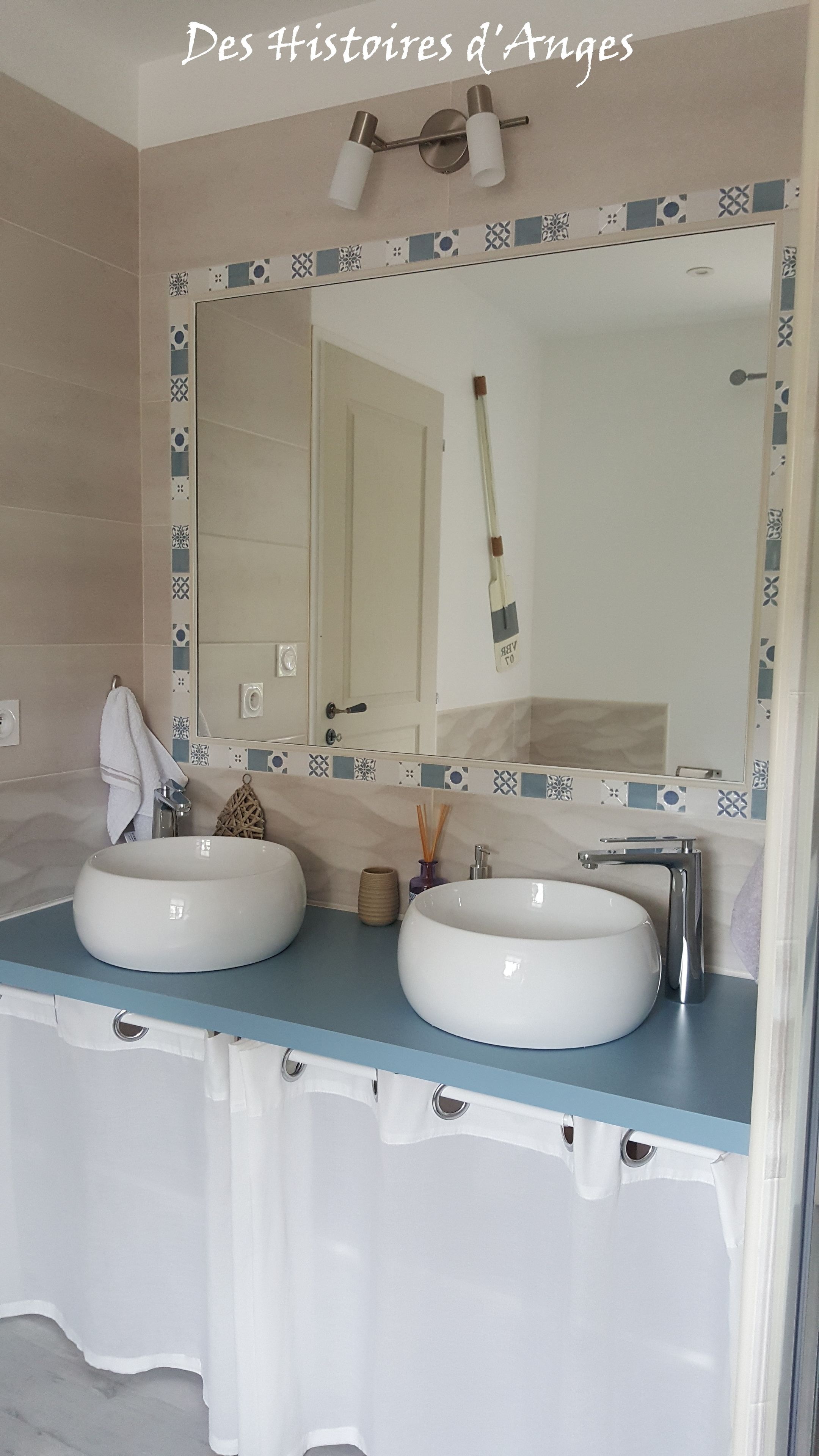 A bathroom with two white sinks, a mirror, and a towel hanging on the wall.